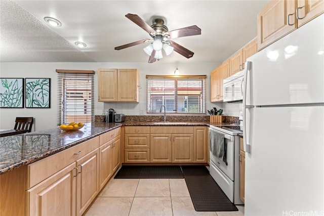 kitchen with plenty of natural light, dark stone countertops, white appliances, and sink