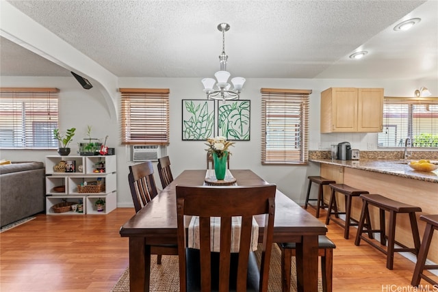 dining space featuring light wood-type flooring, sink, a wealth of natural light, and a chandelier