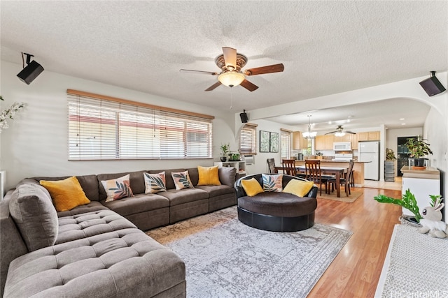 living room featuring ceiling fan, a textured ceiling, a wealth of natural light, and light hardwood / wood-style flooring