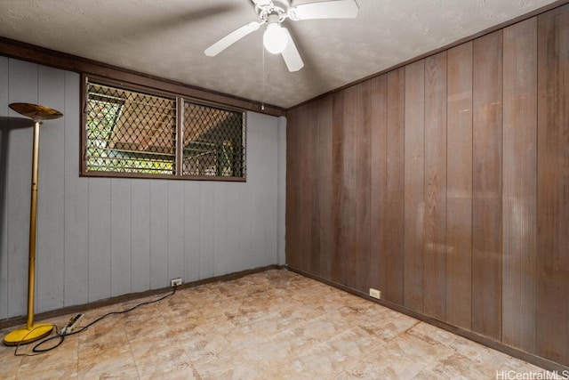 unfurnished room with ceiling fan, a textured ceiling, and wood walls