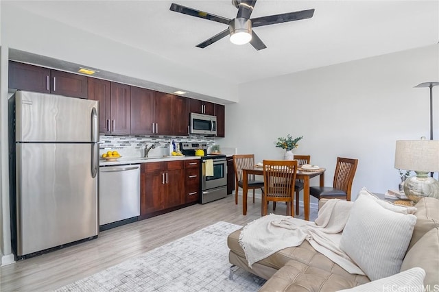 kitchen with appliances with stainless steel finishes, tasteful backsplash, ceiling fan, sink, and light hardwood / wood-style floors