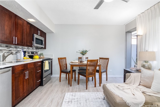 kitchen featuring ceiling fan, sink, backsplash, appliances with stainless steel finishes, and light wood-type flooring