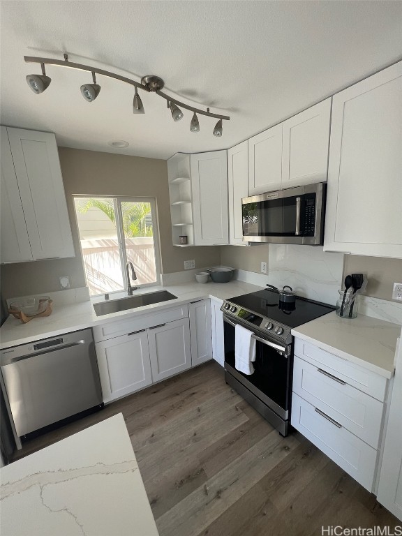 kitchen with stainless steel appliances, white cabinetry, sink, and dark hardwood / wood-style floors