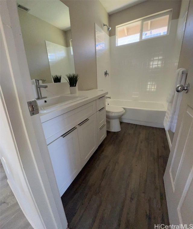 full bathroom featuring tiled shower / bath, vanity, toilet, and hardwood / wood-style floors