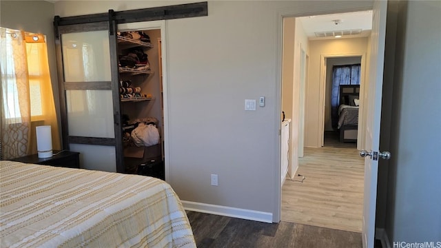 bedroom featuring a barn door, dark hardwood / wood-style floors, a closet, and a spacious closet