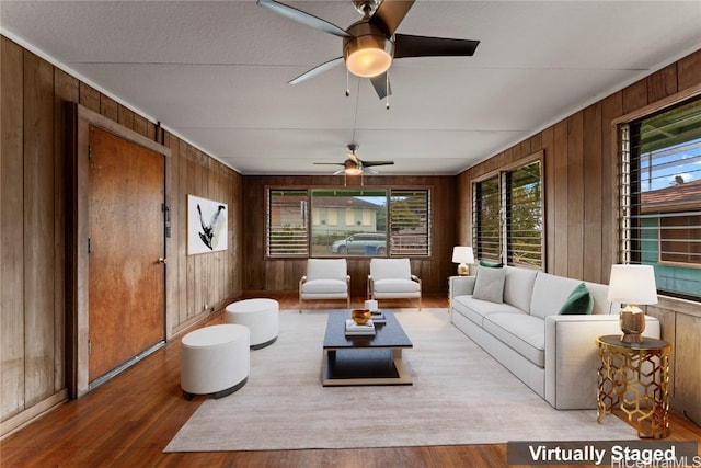 living room featuring hardwood / wood-style flooring, ceiling fan, and wooden walls