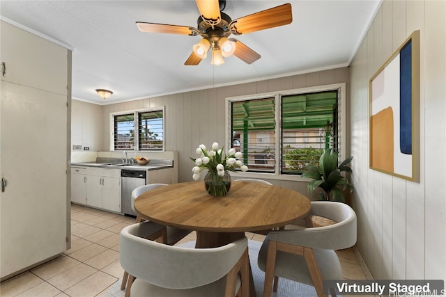 tiled dining space featuring ornamental molding, wood walls, sink, and ceiling fan