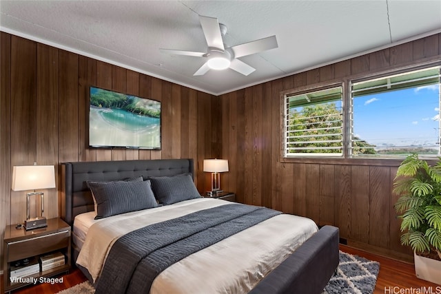 bedroom with hardwood / wood-style floors, ceiling fan, wooden walls, and a textured ceiling