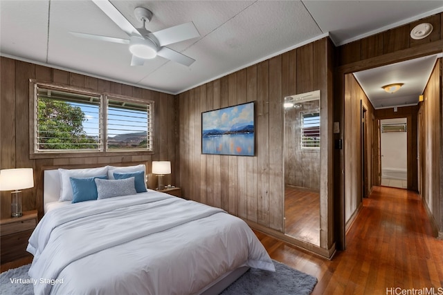 bedroom featuring ornamental molding, wooden walls, hardwood / wood-style flooring, and ceiling fan