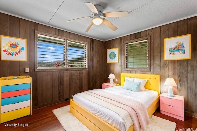 bedroom featuring dark hardwood / wood-style flooring, wood walls, and ceiling fan