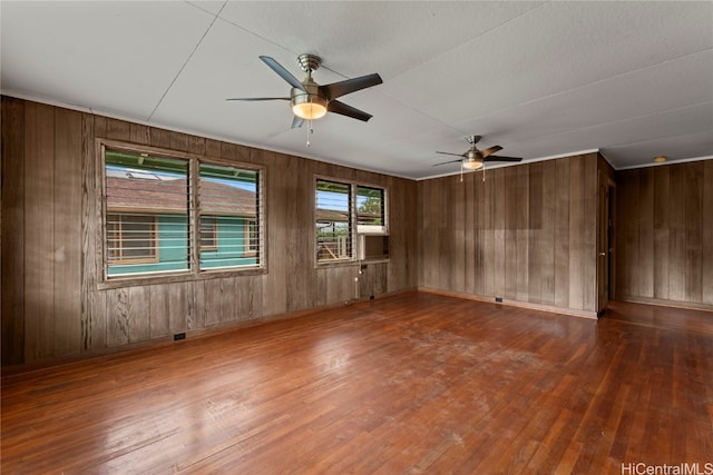 empty room featuring wooden walls, hardwood / wood-style flooring, and ceiling fan