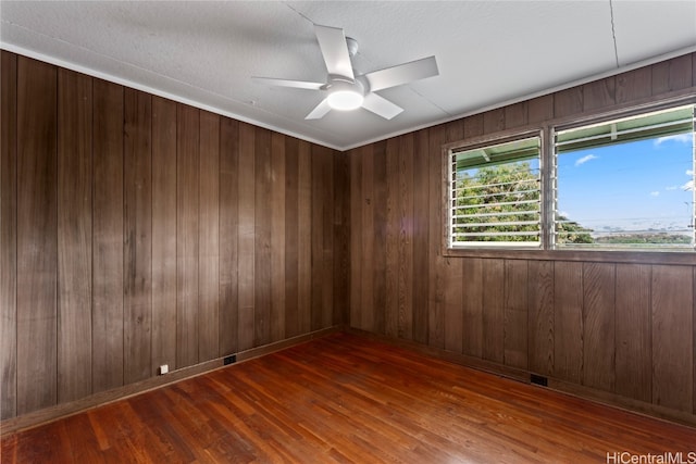 empty room featuring wood walls, ceiling fan, a textured ceiling, and dark hardwood / wood-style flooring