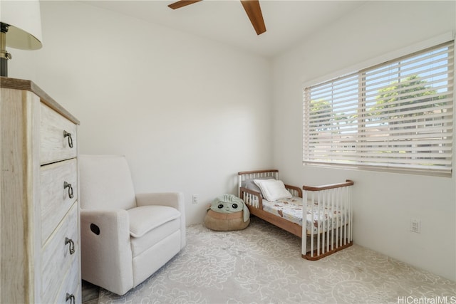 bedroom featuring ceiling fan and a nursery area