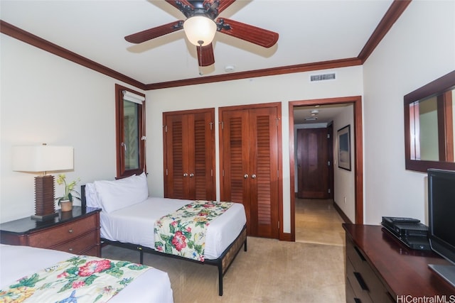 bedroom with ceiling fan, crown molding, multiple closets, and light carpet