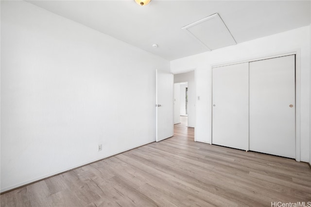 unfurnished bedroom featuring attic access, a closet, and wood finished floors