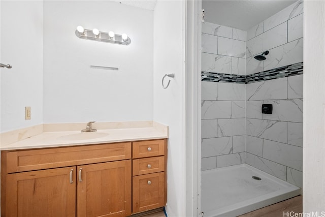 bathroom featuring vanity, a textured ceiling, and a tile shower