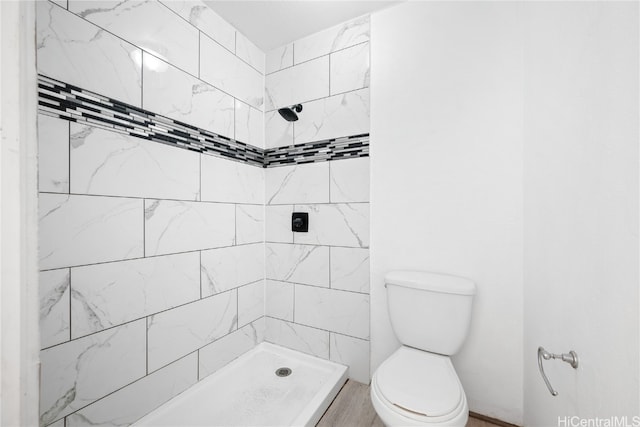 bathroom featuring a tile shower and toilet