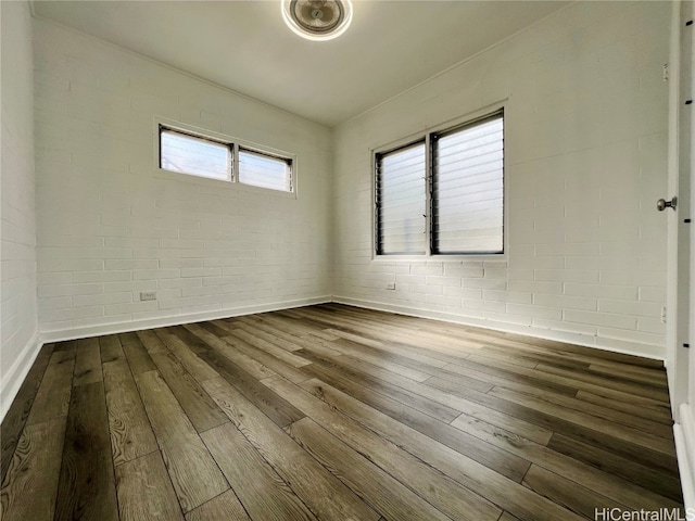 spare room with brick wall and hardwood / wood-style flooring