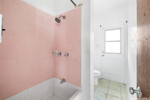 bathroom with a tile shower, toilet, and tile patterned flooring