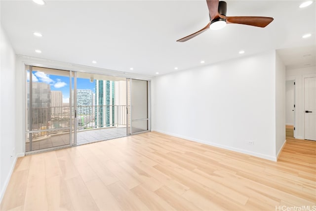 unfurnished room featuring ceiling fan, light hardwood / wood-style flooring, and a wall of windows