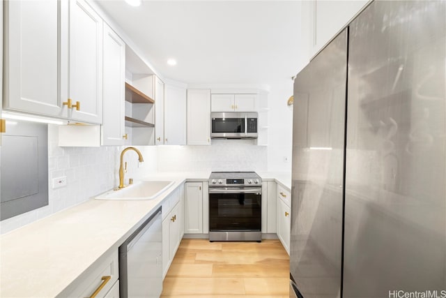 kitchen with sink, white cabinets, light hardwood / wood-style flooring, and stainless steel appliances