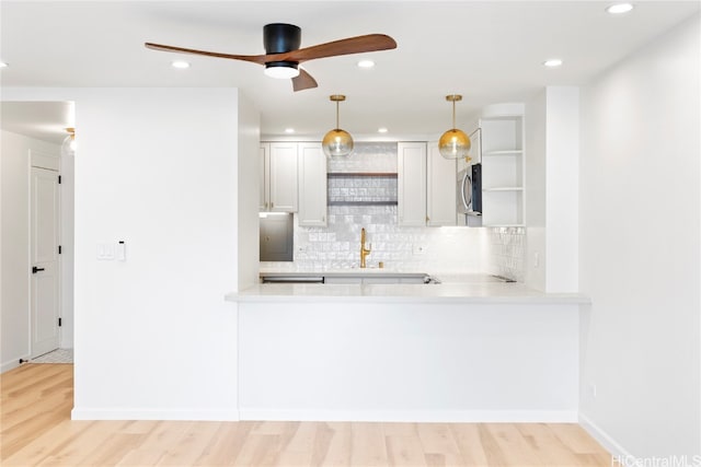 kitchen featuring white cabinetry, backsplash, light wood-type flooring, and hanging light fixtures