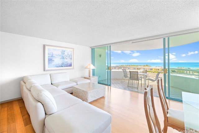 living room featuring a textured ceiling, a water view, and light hardwood / wood-style floors