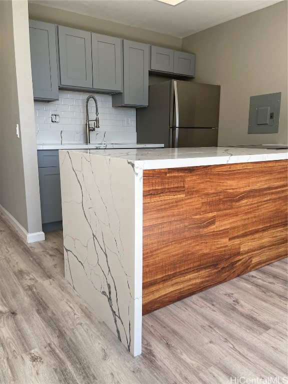 kitchen featuring light hardwood / wood-style flooring, gray cabinetry, and stainless steel refrigerator