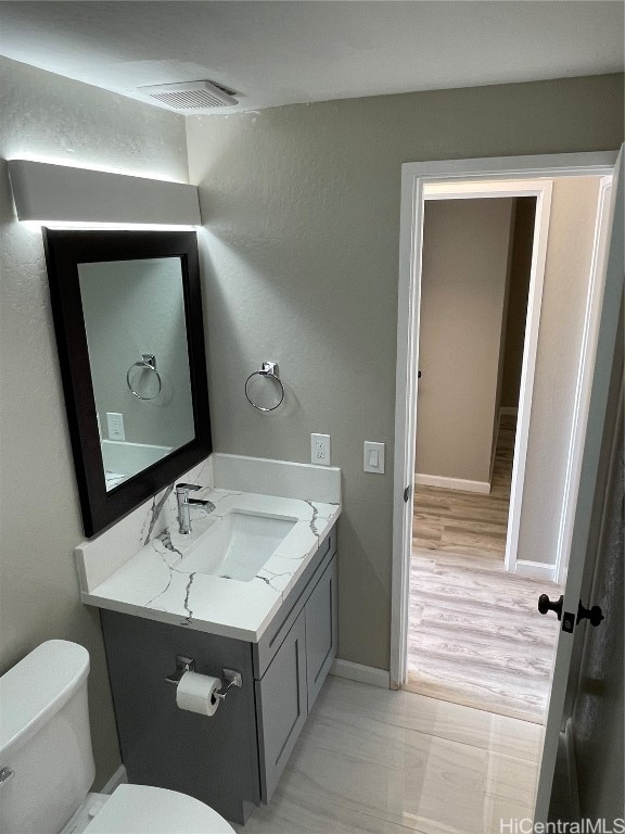 bathroom with vanity, toilet, and wood-type flooring