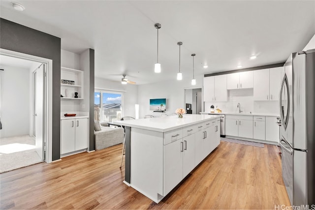 kitchen with a kitchen island, white cabinetry, light hardwood / wood-style flooring, pendant lighting, and stainless steel appliances