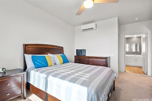 bedroom featuring ensuite bathroom, an AC wall unit, light colored carpet, and ceiling fan