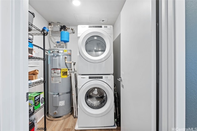 laundry area with secured water heater, wood-type flooring, and stacked washer and dryer