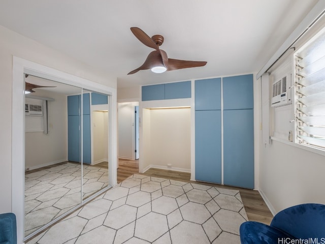 unfurnished bedroom featuring a wall mounted air conditioner, ceiling fan, and light hardwood / wood-style floors