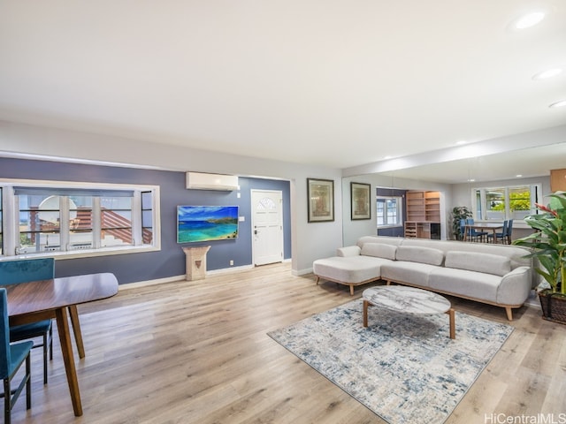 living room with a wall mounted air conditioner and light hardwood / wood-style flooring