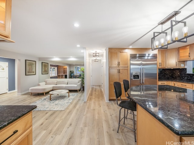 kitchen featuring a center island, a kitchen breakfast bar, stainless steel built in fridge, light wood-type flooring, and decorative light fixtures