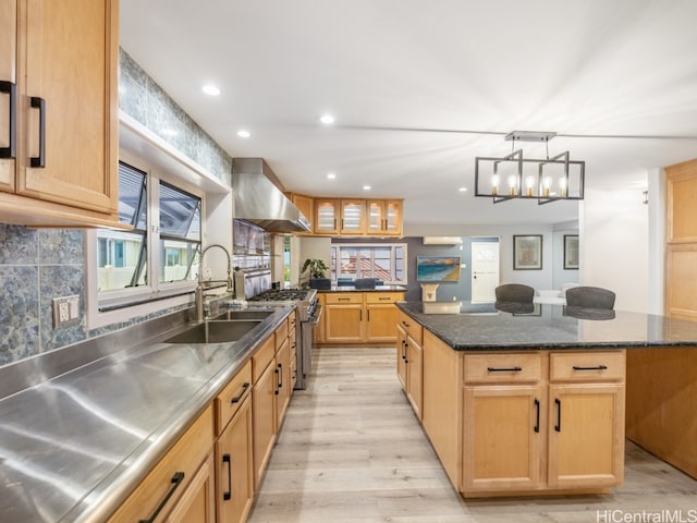 kitchen featuring high end range, light wood-type flooring, wall chimney exhaust hood, stainless steel counters, and a kitchen island