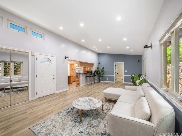 living room featuring a wealth of natural light, high vaulted ceiling, and light hardwood / wood-style floors