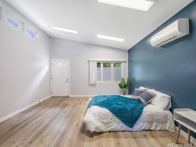 bedroom with a wall mounted AC, light hardwood / wood-style flooring, and lofted ceiling