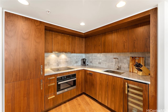 kitchen featuring beverage cooler, stainless steel oven, light hardwood / wood-style flooring, black electric stovetop, and sink