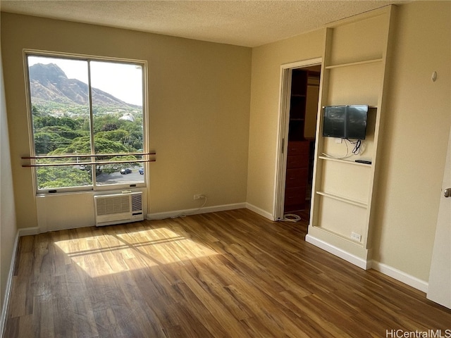 spare room with a mountain view, hardwood / wood-style flooring, and a textured ceiling