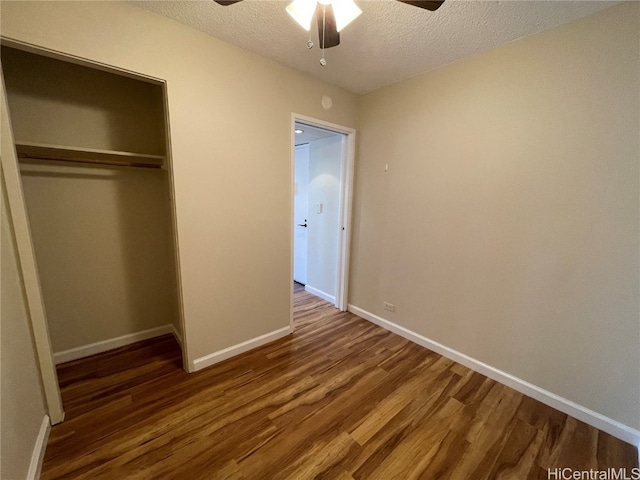 unfurnished bedroom with a closet, ceiling fan, a textured ceiling, and dark hardwood / wood-style flooring