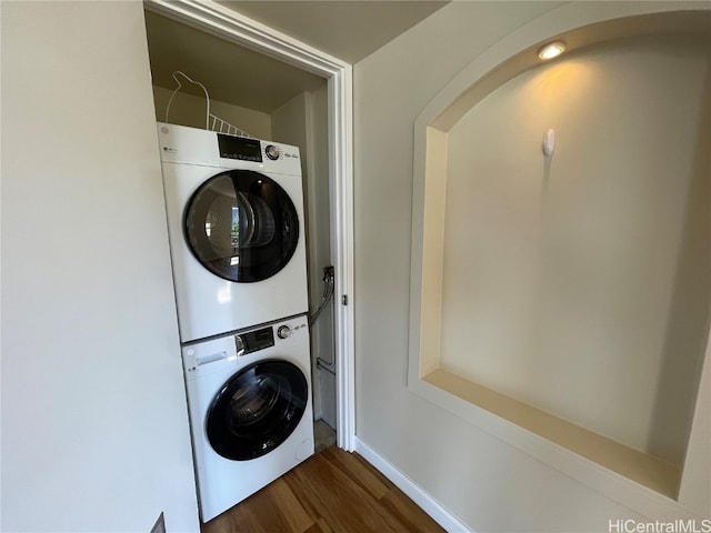 laundry area featuring stacked washer / dryer and dark hardwood / wood-style flooring