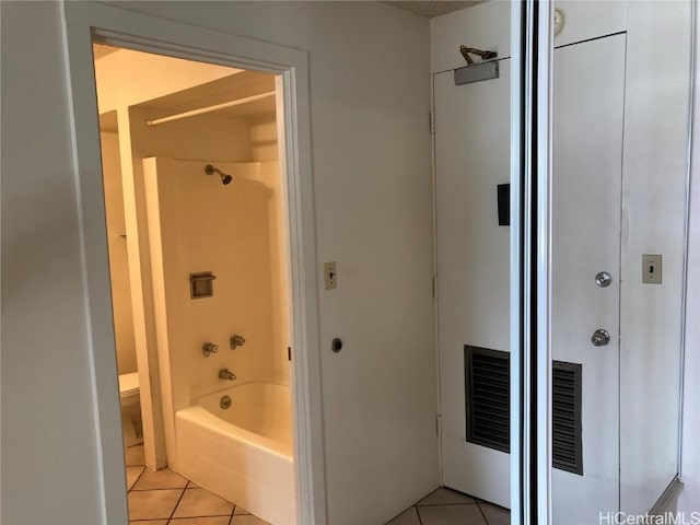 bathroom with washtub / shower combination, toilet, and tile patterned flooring