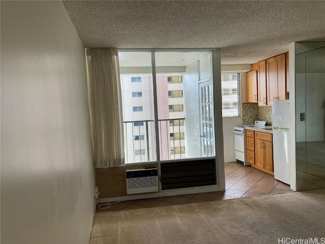 interior space featuring a wall unit AC, decorative backsplash, white appliances, light colored carpet, and a textured ceiling