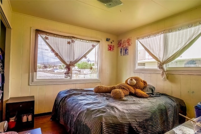 bedroom with dark hardwood / wood-style flooring and wooden walls