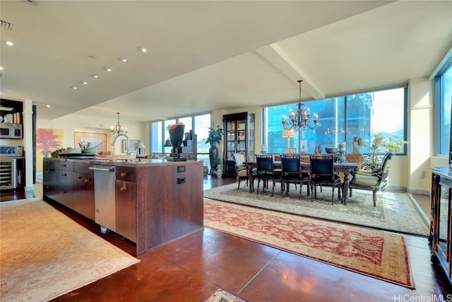 kitchen with pendant lighting, sink, stainless steel dishwasher, an island with sink, and a notable chandelier