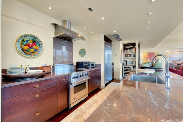 kitchen with sink, premium appliances, beverage cooler, and wall chimney range hood