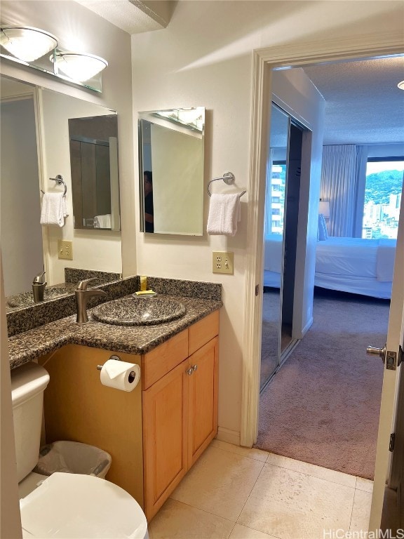 bathroom with vanity, toilet, a textured ceiling, and tile patterned flooring