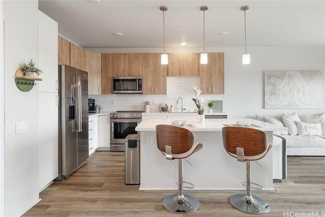 kitchen featuring backsplash, a breakfast bar, stainless steel appliances, and light hardwood / wood-style flooring