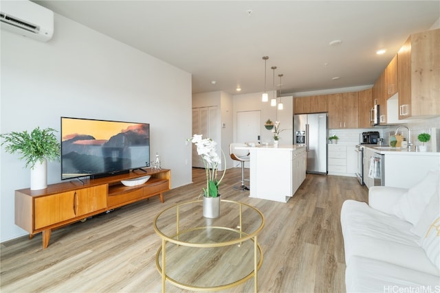 living room featuring a wall mounted air conditioner, light wood-type flooring, and sink